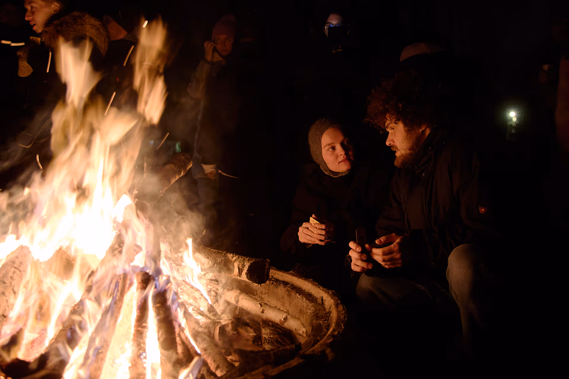 Camp participants sharing experiences around the campfire on the first day, building genuine connections through structured activities | Timestripe
