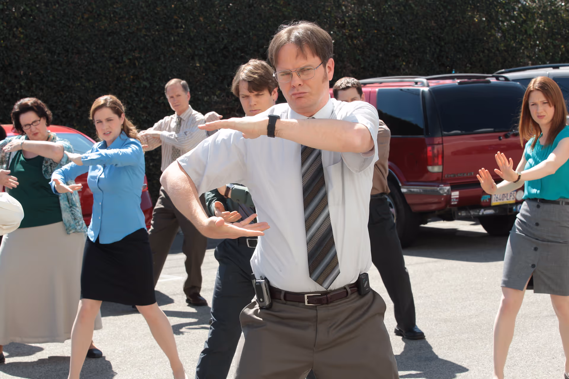 Dwight Schrute leading his coworkers in a Tai Chi exercise in the parking lot outside the office
